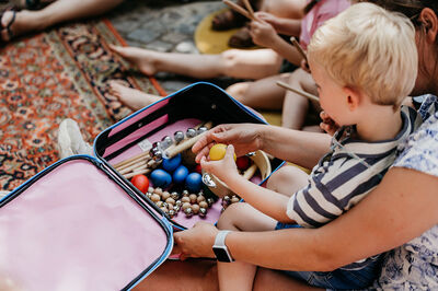 Ouders en kinderen doen mee met een muziekworkshop voor de allerkleinsten op een plein.