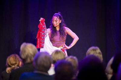 Een danseres treed op en heeft een rode doek in haar hand.
