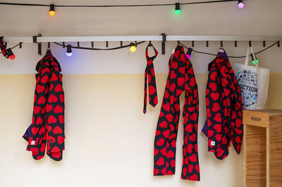 Roze kleding met hartenpatroon hangt aan een lijn, verlicht door kleurrijke lampjes.