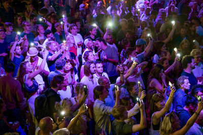 Een menigte mensen met telefoons met felle lichtjes, gefocust tijdens een evenement of concert.