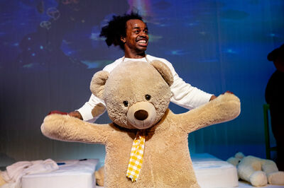 Een persoon danst met een grote teddybeer in een voorstelling.