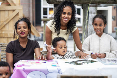 Twee ouders en twee kinderen zitten bij een lage tafel met stiften.