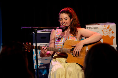 Persoon speelt de acoustische gitaar en zingt in een microfoon.