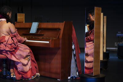 Een persoon speelt piano. Daarnaast staat een spiegel, waardoor het gezicht van de persoon te zien is.