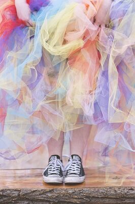 Een gekleurde rok met sneakers eronder.