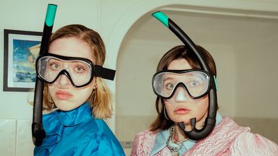 Foto van twee mensen die binnen staan, met snorkelbril en snorkel op hun hoofden.