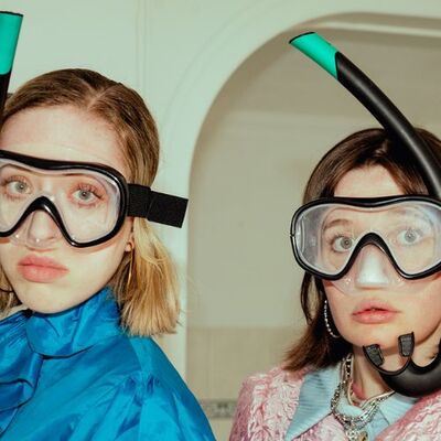 Foto van twee mensen die binnen staan, met snorkelbril en snorkel op hun hoofden.