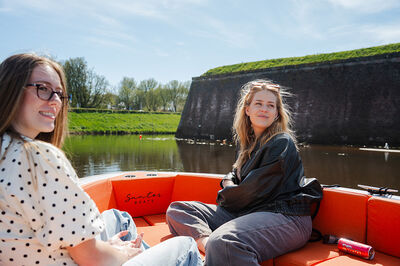 Twee personen zitten in een oranje bootje.