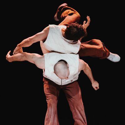 Een danser rolt zijwaards over de rug van een ander.