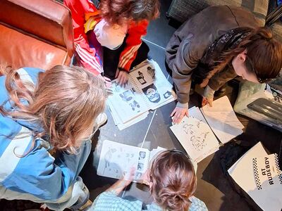 Mensen volgen een tekenworkshop en zitten samen aan tafel.