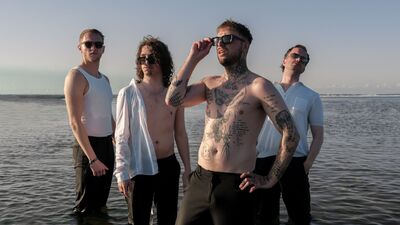 Een bandfoto van 4 mensen op het strand.