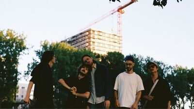 Een bandfoto van 5 mensen.