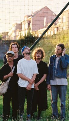 Een bandfoto van 5 mensen.