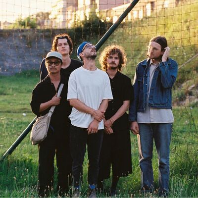 Een bandfoto van 5 mensen.