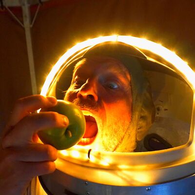 Het hoofd van een persoon in een verlichtte astronouten helm. De persoon een een appel.
