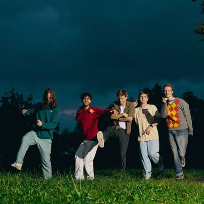 Een bandfoto van 5 mensen.
